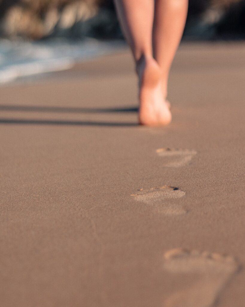 Pieds nus marchant au bord de l eau, laissant des empreintes dans le sable